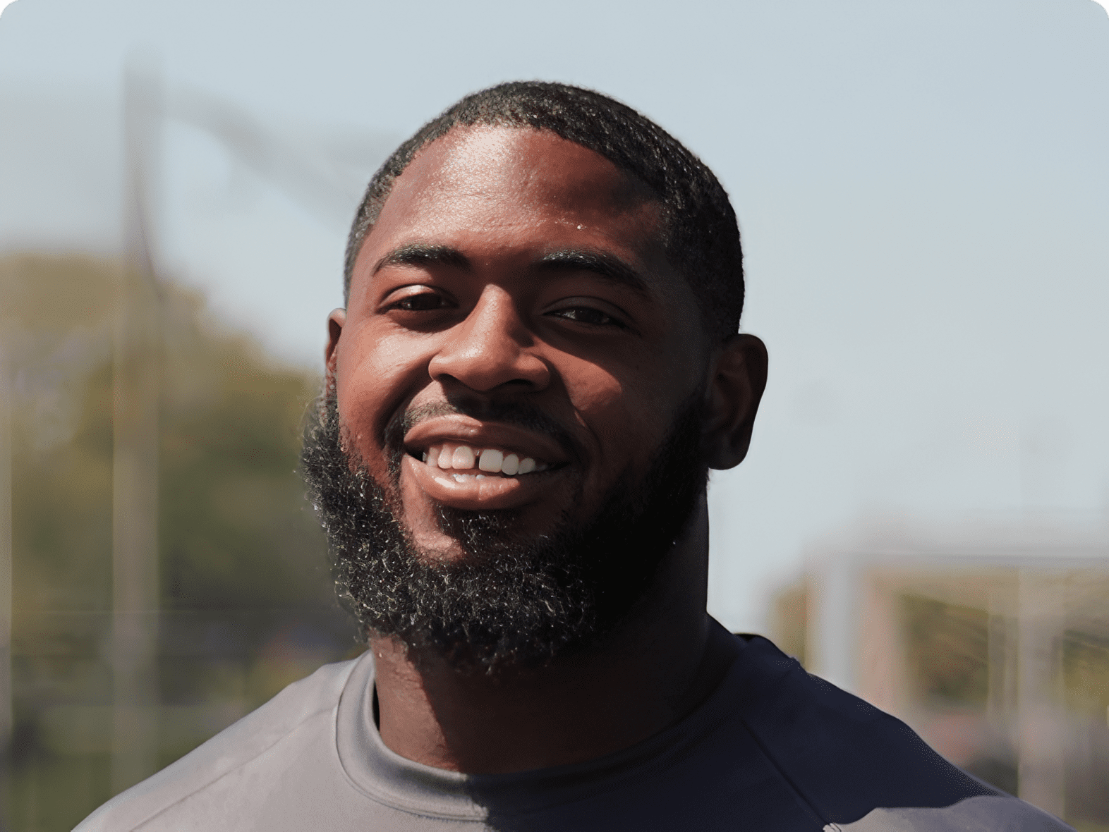 Smiling man outdoors with blurred background.