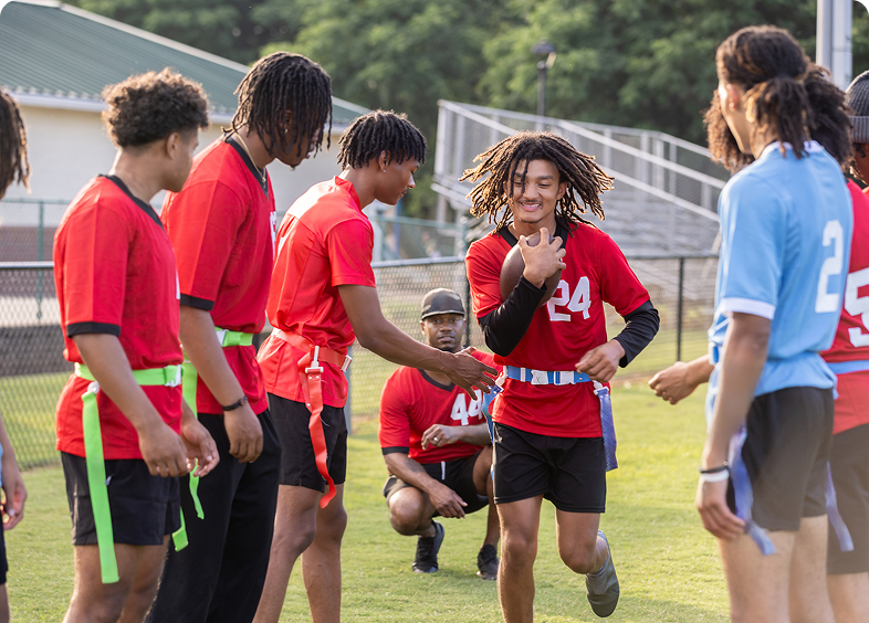Youth playing flag football on grassy field.